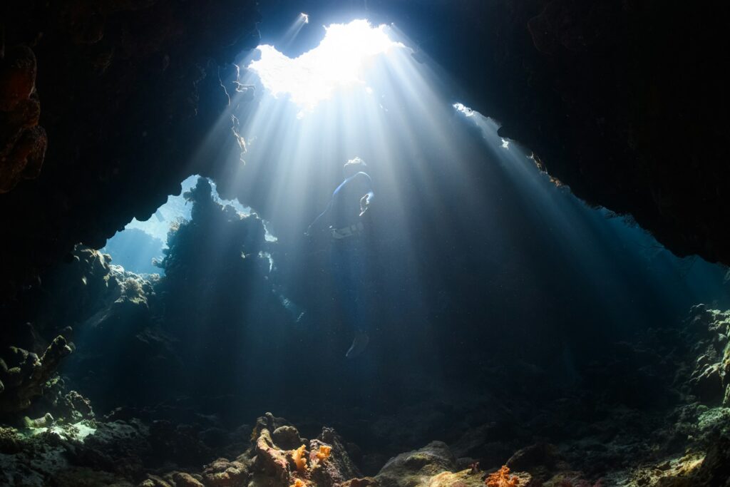 a sunbeam shines through a cave in the ocean