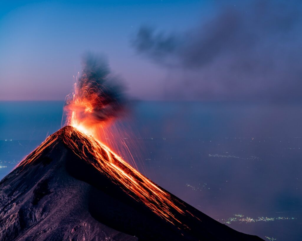 A volcano erupts, spewing smoke and lava into the sky, showcasing nature's raw power and beauty.