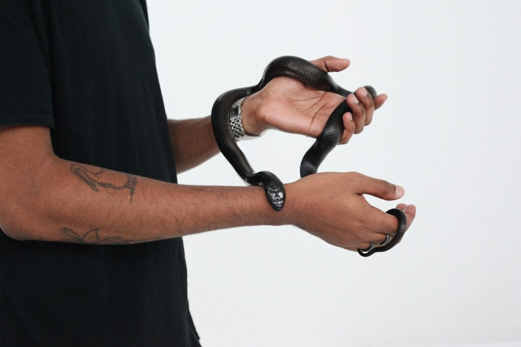 A man confidently holds a snake in his hand, showcasing a unique bond with the creature.