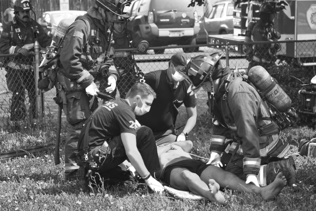 A team of firefighters assists an injured man on the ground, showcasing their commitment to saving lives during emergencies.
