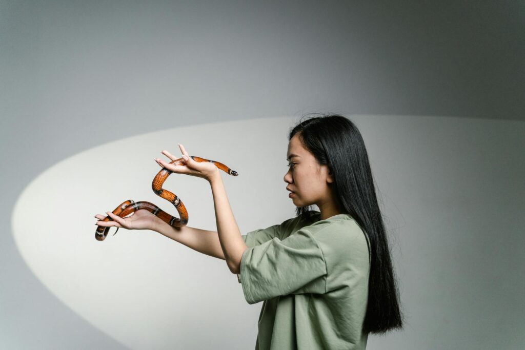 A woman gently cradles a snake in her hands, showcasing her connection with the creature.